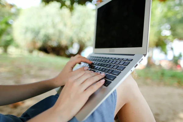 Feminino boas mãos usando laptop com areia no fundo, tela preta . — Fotografia de Stock