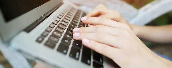 Website header and banner of closeup female hands typing on laptop keyboard.