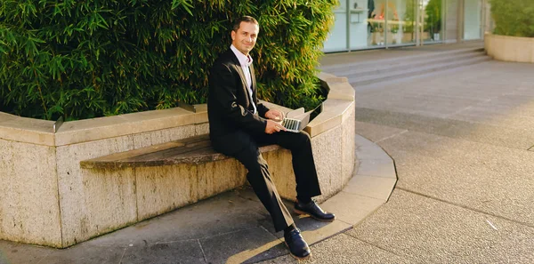 Businessman working with laptop outside near plant in  .