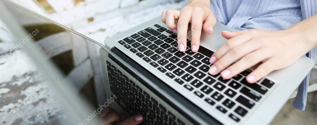 Website banner of closeup female hands typing on laptop keyboard.