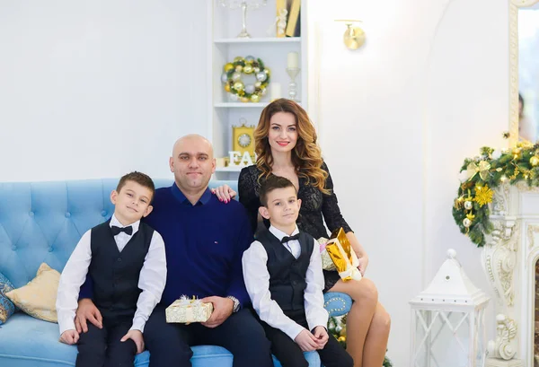 Jovem mãe feliz e pai sentado no sofá com filhos no quarto decorado para férias de Natal . — Fotografia de Stock