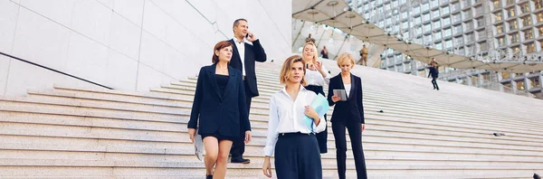 Financial team going down stairs in   with tablet, case and talk