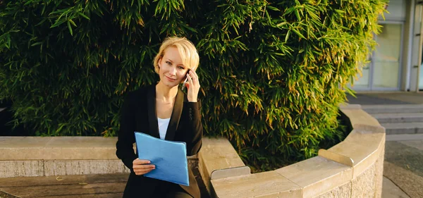 Affärskvinna som talade genom smartphone utanför med dokumentet fall. — Stockfoto