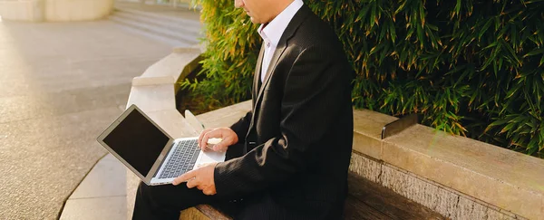 Empresário trabalhando com laptop fora perto da planta em   . — Fotografia de Stock