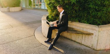 İşadamı çevre bitki dışarıda dizüstü bilgisayar ile çalışma  .