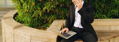 Smartphone ile konuşmak ve içinde dışında laptop ile çalışan Yöneticisi