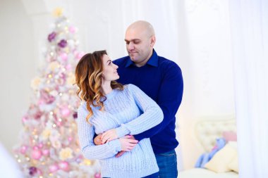 Genç karı sarılma koca köknar ree yakınındaki. Mutlu bir aile ve Noel ve yeni yıl, kış tatil atmosferinde kutluyor kavramı.