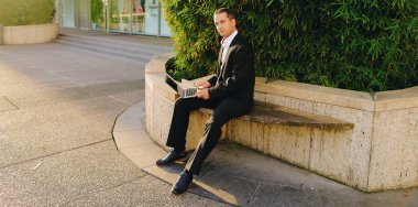 İşadamı çevre bitki dışarıda dizüstü bilgisayar ile çalışma  .