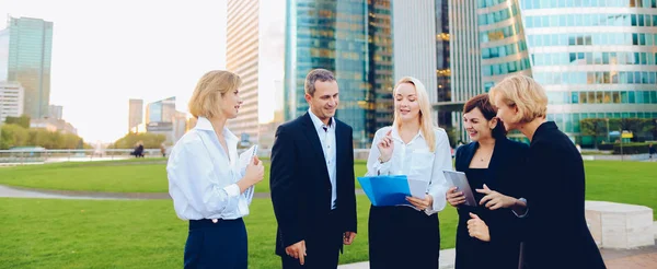 Employees of large corporation going with document case, laptop