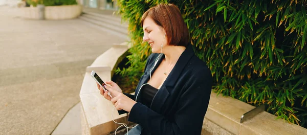 Secretaria escuchando música con auriculares y smartphone o — Foto de Stock