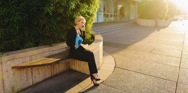 Secretaria hablando por teléfono inteligente con estuche de documentos al aire libre — Foto de Stock