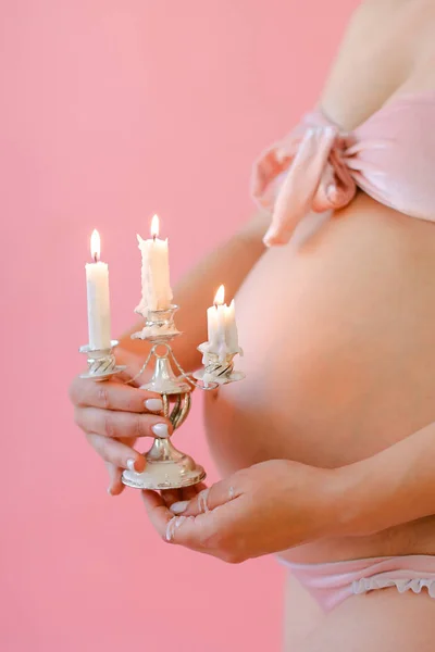 Primo piano donna incinta in biancheria intima tenendo pancia e mantenendo le candele . — Foto Stock