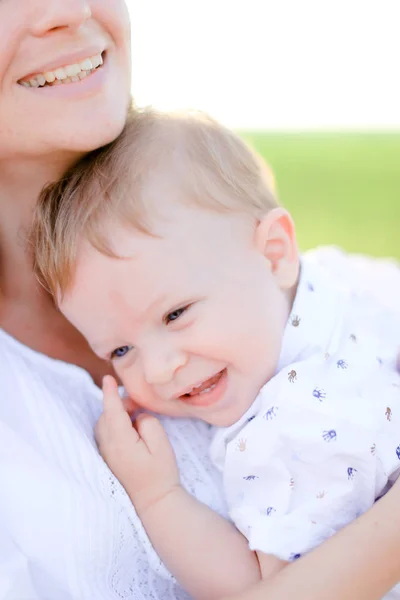 Giovane madre che tiene il piccolo bambino sullo sfondo verde . — Foto Stock