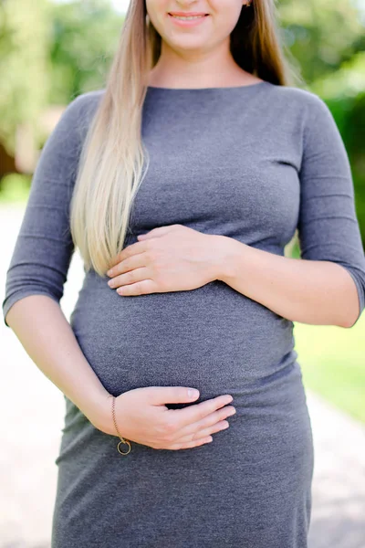 Jovem grávida vestindo vestido cinza segurando barriga . — Fotografia de Stock