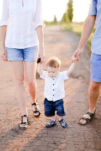 Bambino che tiene per mano i genitori e cammina sulla strada . — Foto Stock