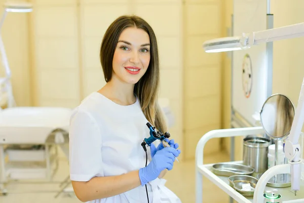 Junge permanente Visagistin sitzt mit Mikroblading-Gerät im Schönheitssalon. — Stockfoto