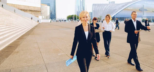 Businesswoman from back passing in   with blue document case in