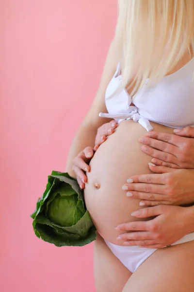 Беременная блондинка в нижнем белье держит живот и держит капусту . — стоковое фото