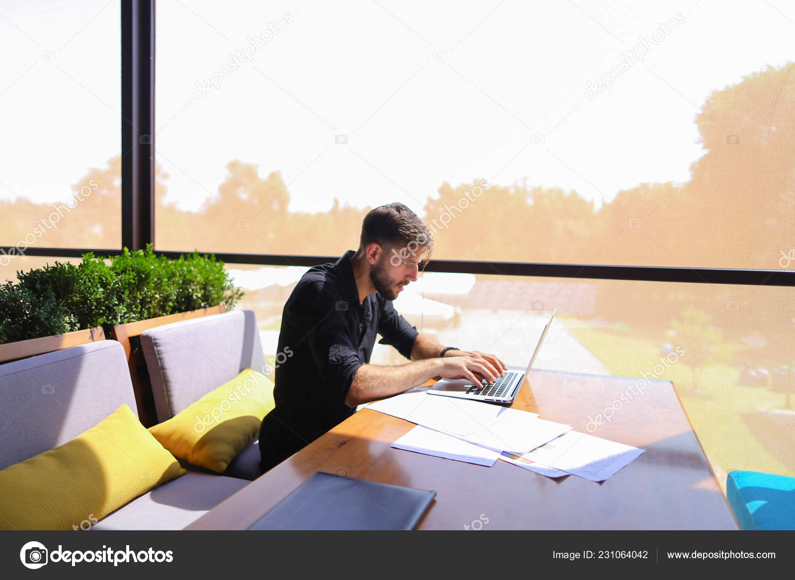 Quantity Surveyor Working At Cafe Table With Papers And Laptop