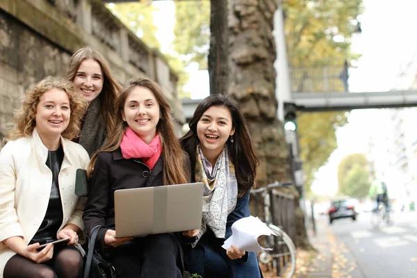 Kvinnliga studenter som sitter på bänken och lärande med laptop och pa — Stockfoto