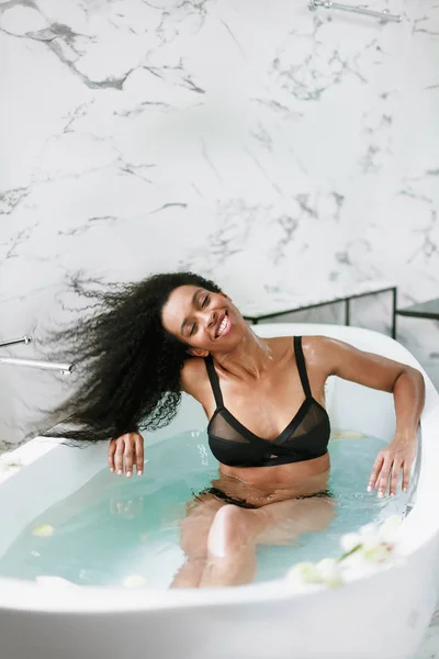 Schattig jong zwart meisje nemen bad en dragen zwarte zwembroek. — Stockfoto