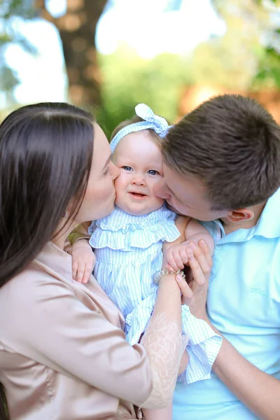 Молоді батьки цілують маленьку доньку . — стокове фото