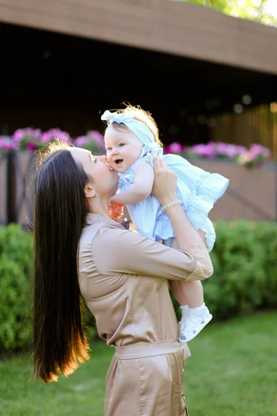 Junge glückliche Frau hält und küsst kleine Tochter. — Stockfoto