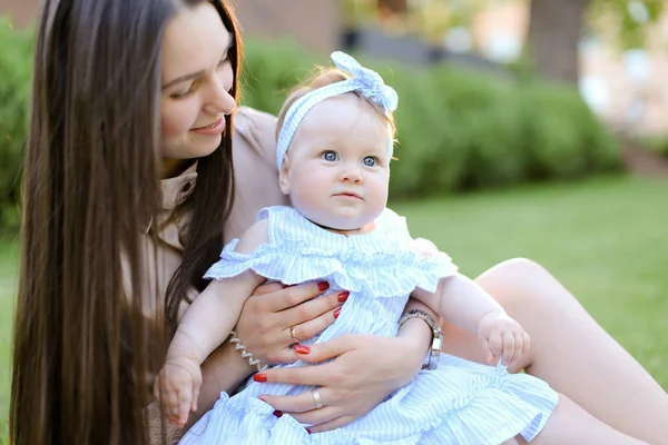 Giovane madre caucasica seduta sull'erba con piccola figlia . — Foto Stock