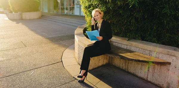 Secretaria hablando por teléfono inteligente con estuche de documentos al aire libre — Foto de Stock