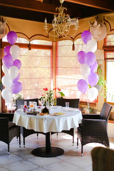 Comida en la mesa en la cafetería y globos blancos violeta . — Foto de Stock