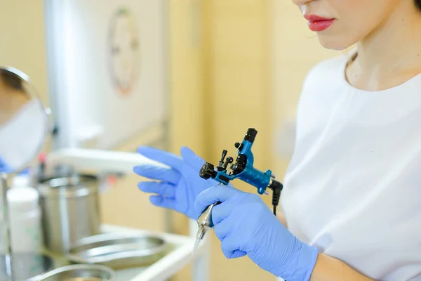 Κοντινό cosmetlogist χέρια σε μπλε γάντια λατέξ κρατώντας microblading μηχανή στο σαλόνι ομορφιάς. — Φωτογραφία Αρχείου