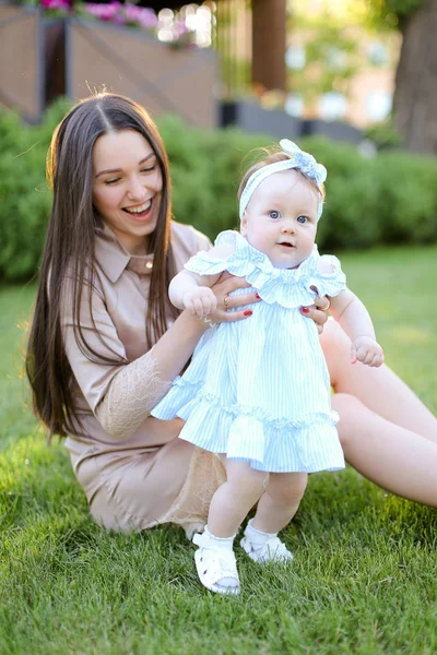 Giovane madre sorridente seduta sull'erba con piccola figlia . — Foto Stock