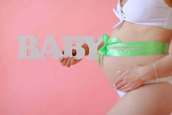 Primo piano donna incinta in biancheria intima bianca con nastro sulla pancia mantenere iscrizione bambino . — Foto Stock