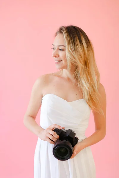 Jovem fotógrafa feminina alegre com câmera em fundo monofônico rosa . — Fotografia de Stock