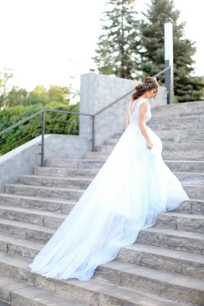 Achteraanzicht van de Kaukasische verloofde lopen op betonnen trappen en dragen witte jurk. — Stockfoto