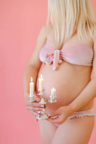 Blonde young pregnant woman in underwear holding belly and keeping candles. — Stock Photo, Image