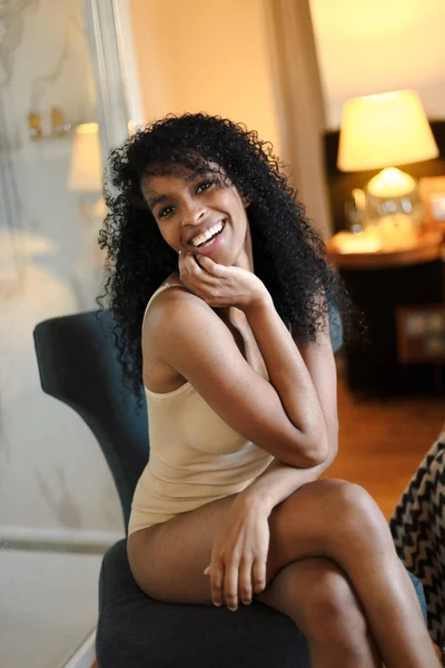 Jeune fille afro américaine heureuse portant des sous-vêtements et assise dans la chambre . — Photo