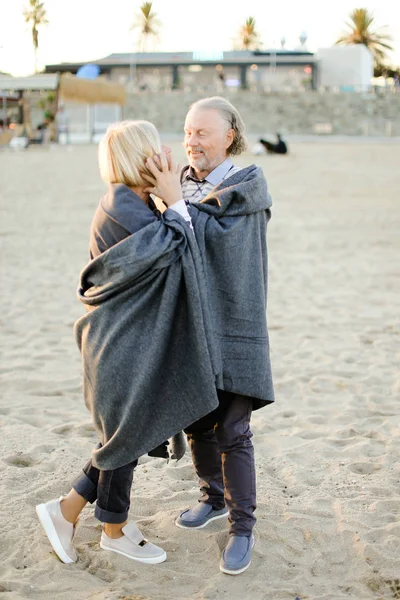老公抱着妻子, 穿着格子衣服, 站在沙滩上. — 图库照片