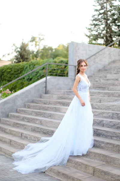 Καυκάσιος γοητευτική νύφη στέκεται σε σκυρόδεμα σκάλες και φορώντας λευκό φόρεμα. — Φωτογραφία Αρχείου