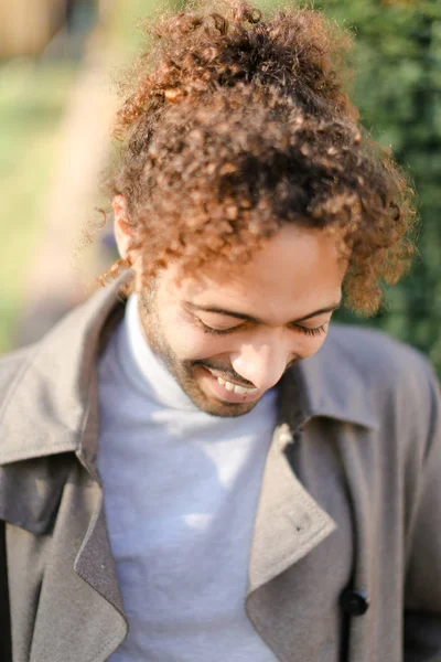 Porträt eines afroamerikanischen Mannes mit lockigem Haar, der lächelt und draußen steht. — Stockfoto