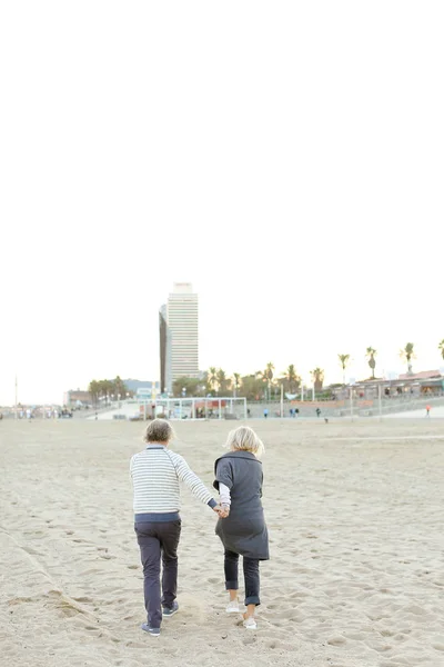 砂浜を走り、手をつないでいる先輩夫婦. — ストック写真