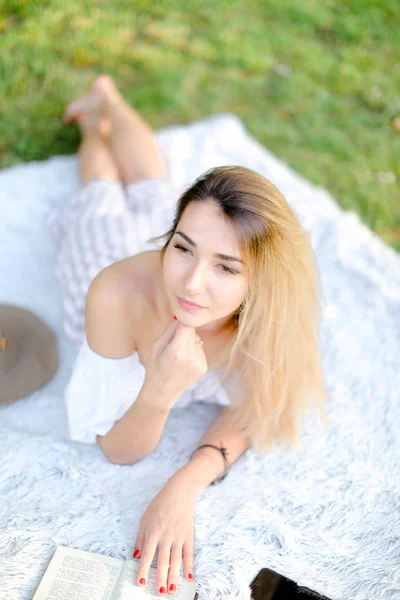 Chica joven acostada en cuadros en el parque y libro de lectura . — Foto de Stock