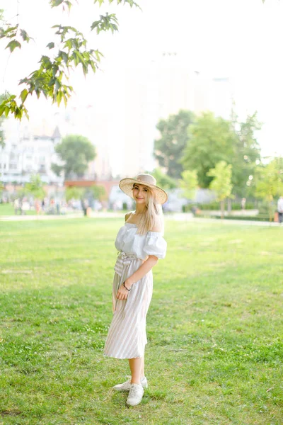 Jeune fille portant chapeau et robe, debout dans le parc . — Photo