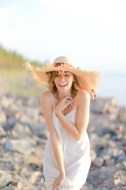 Kiremit plajında duran şapkalı genç kadın..