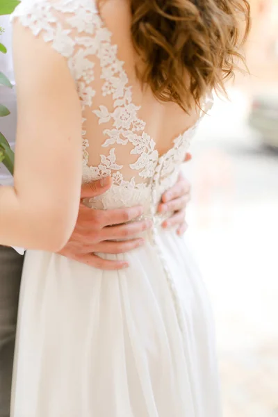 Bruidegom handen knuffelen bruid dragen jurk. — Stockfoto
