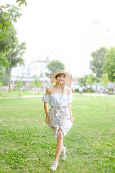 Şapka ve elbise giyen, parkta duran genç ve güzel bir kadın.. — Stok fotoğraf