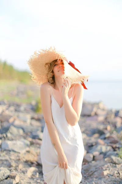 Young happy woman in hat standing on shingle beach. — Stock Photo, Image