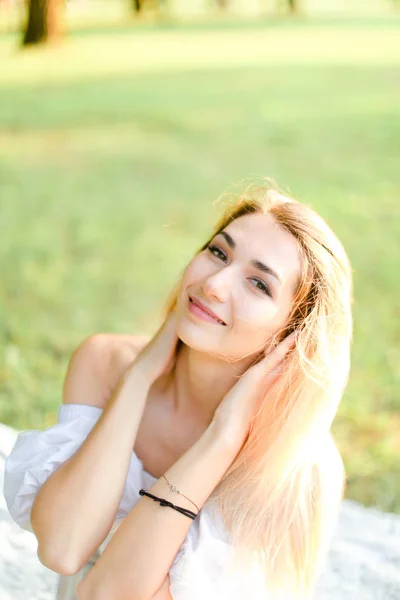 Retrato de jovem loira feliz menina sentado no xadrez, grama no fundo . — Fotografia de Stock