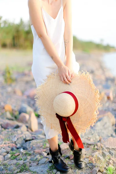 Persona femminile caucasica in piedi sulla spiaggia di ghiaia con cappello in mano . — Foto Stock