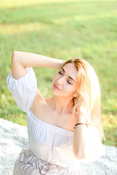 Retrato de una joven rubia caucásica sentada a cuadros, hierba en el fondo . — Foto de Stock